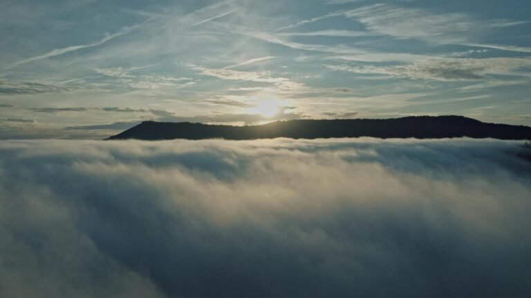 Aerial landscape of Kintzheim at sunrise with mist over hills and vibrant sky.