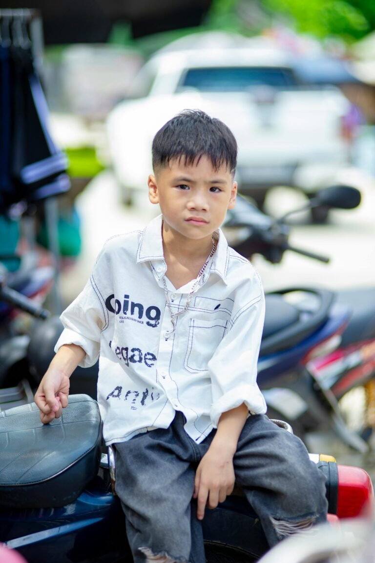 A Vietnamese boy casually poses on a motorbike outdoors, showcasing urban life.