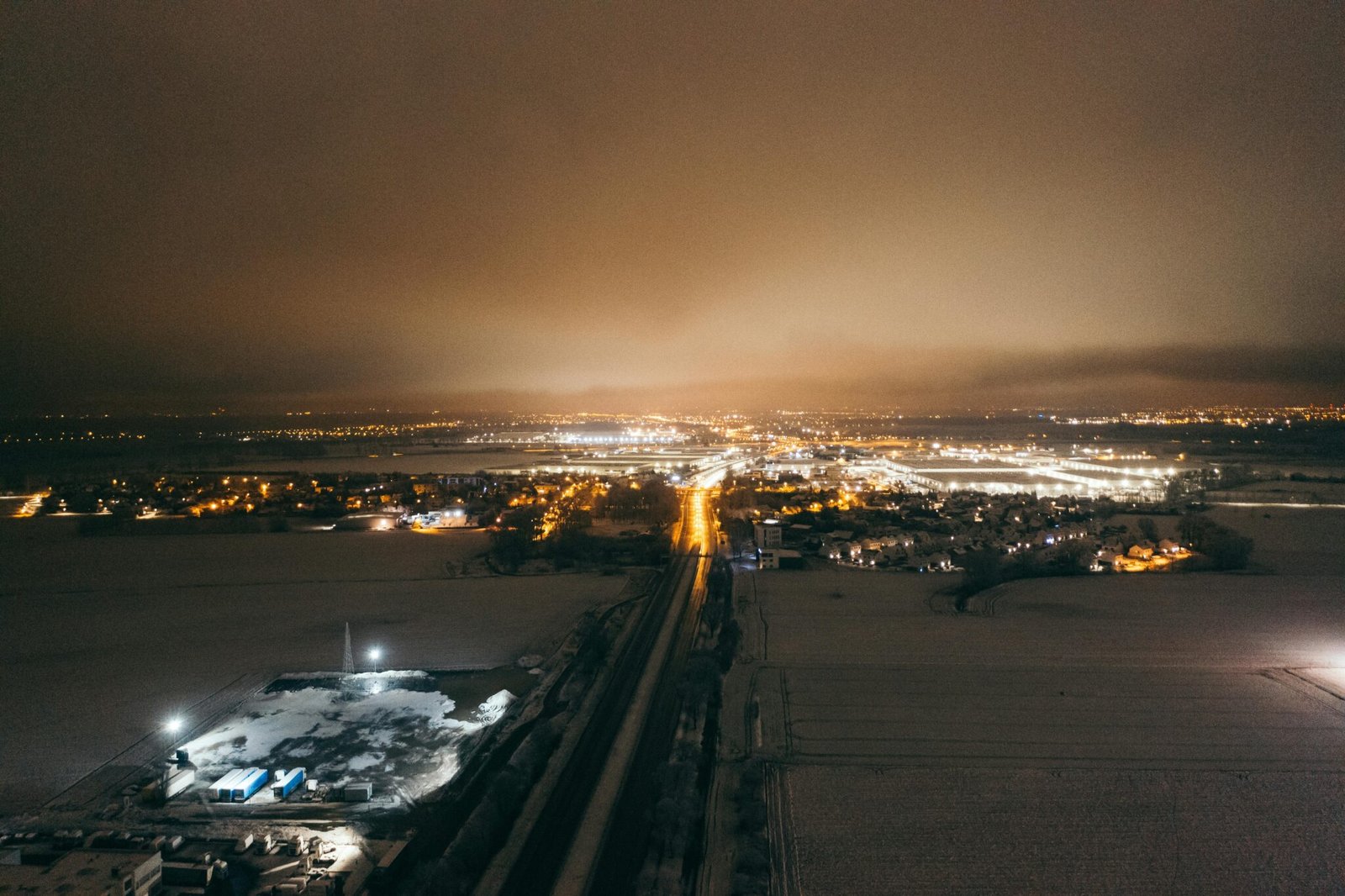 A captivating aerial view of Poznań, Poland at night, showcasing a winter landscape and city lights.