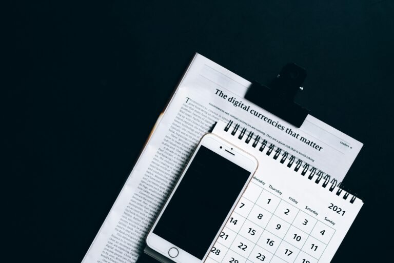 A smartphone placed on a newspaper and calendar, symbolizing modern digital finance.