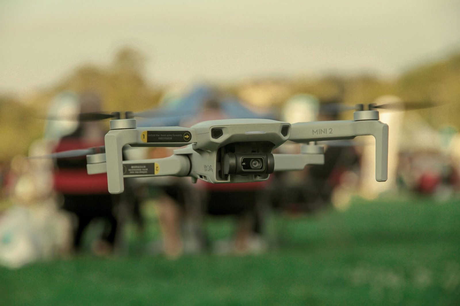 A DJI Mini 2 drone captured in mid-air outdoors with a blurred background.
