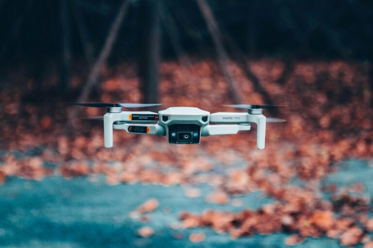 Close-up of a drone flying outdoors amidst autumn leaves, showcasing technology in nature.