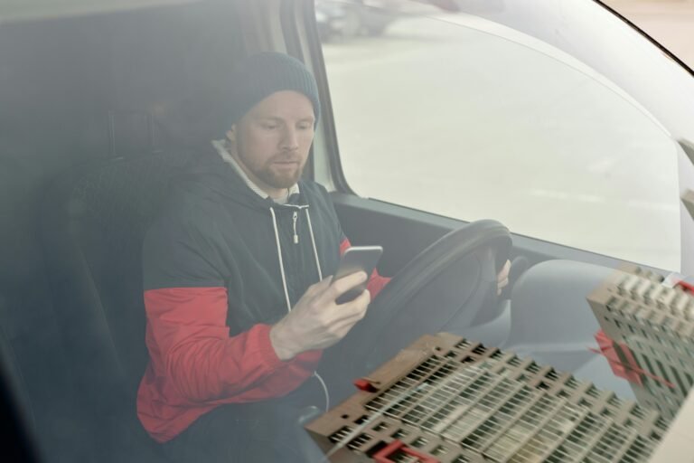 Man in a van using a smartphone, possibly for navigation or communication, while parked.